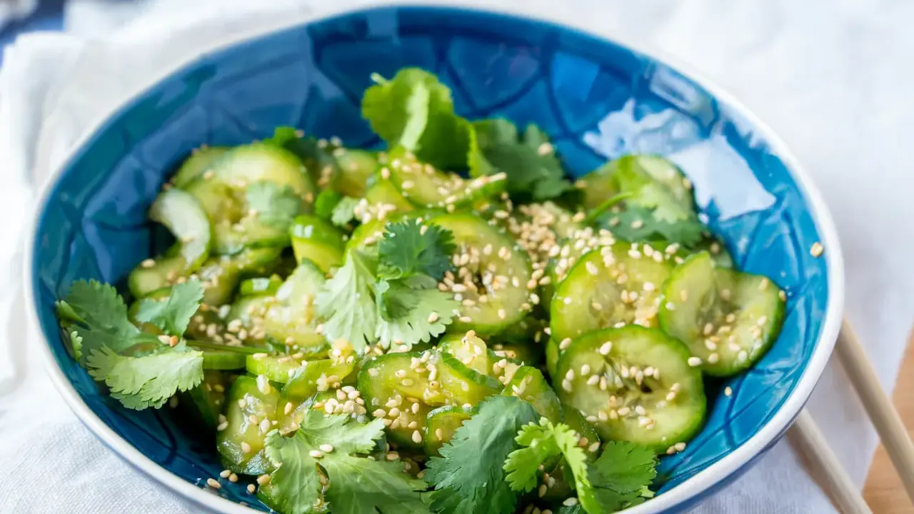 Frischer Gurkensalat mit Sojasauce, Koriander und Sesam in einer blauen Schüssel.