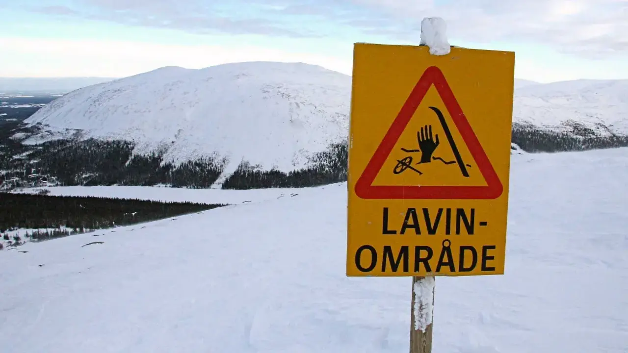 Varning för lavin vid Kebnekaise. Ett gult varningsskylt med en hand, skidor och rep i en röd triangel.