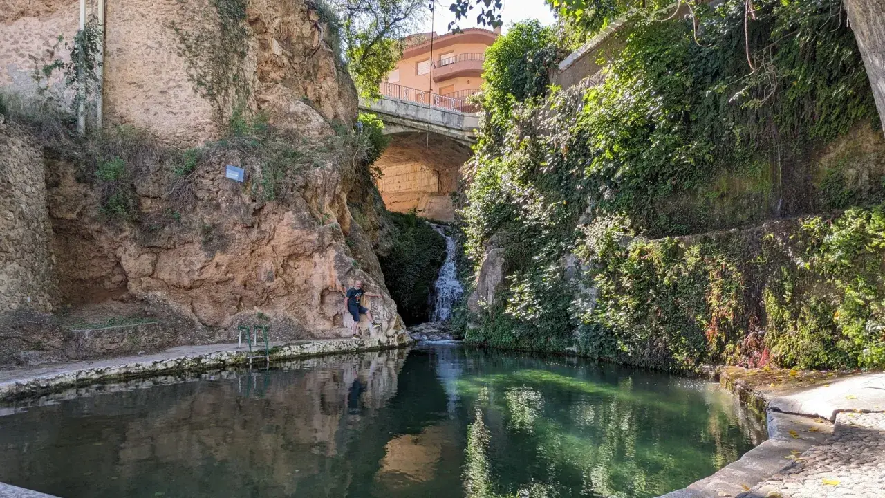 Un hombre posa junto a una cascada en un estanque natural en Ferez, Albacete.