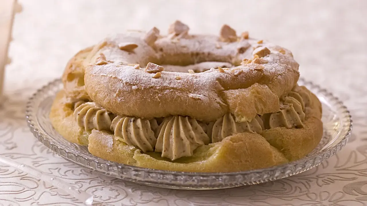 Un Paris-Brest, plat typique d'Île-de-France, garni de crème onctueuse et saupoudré de sucre glace et d'amandes.