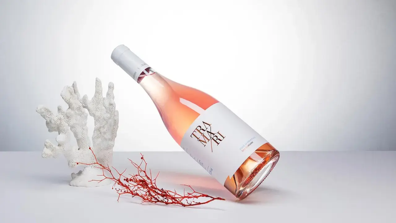 Flasche Roséwein von Cantine San Marzano, umgeben von Korallen und Seetang, auf hellem Hintergrund.