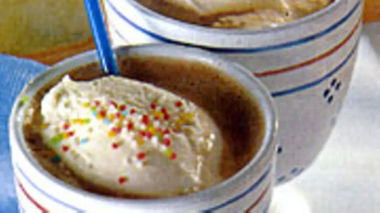 Zwei Becher mit cremigem Vanilleeis, bestreut mit bunten Streuseln. Ein köstliches Eiscafe Rezept für heiße Tage.