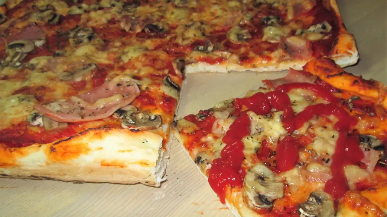Pyszna pizza na cienkim cieście z pieczarkami i szynką, polana ketchupem. Idealna na szybki obiad.