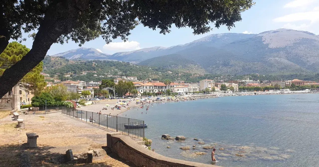 Vista panoramica di Sapri: una spiaggia affollata, il mare azzurro e le montagne sullo sfondo. Ecco cosa vedere a Sapri per una vacanza indimenticabile.