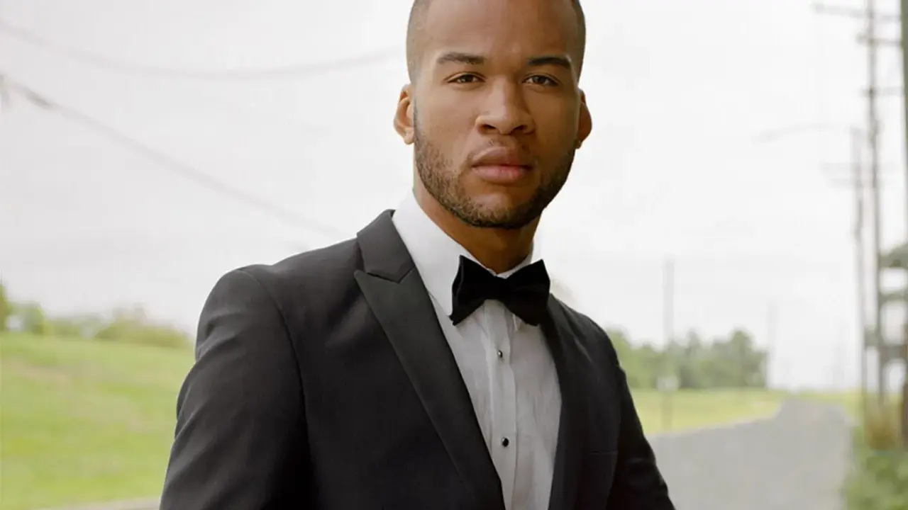 A man in a black tuxedo with a bow tie, ready for black tie weddings.