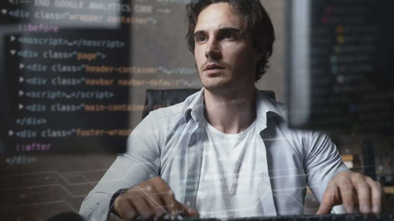 Mężczyzna pracuje nad kodem, tworząc aplikację full stack. W tle widać fragmenty kodu HTML i JavaScript.