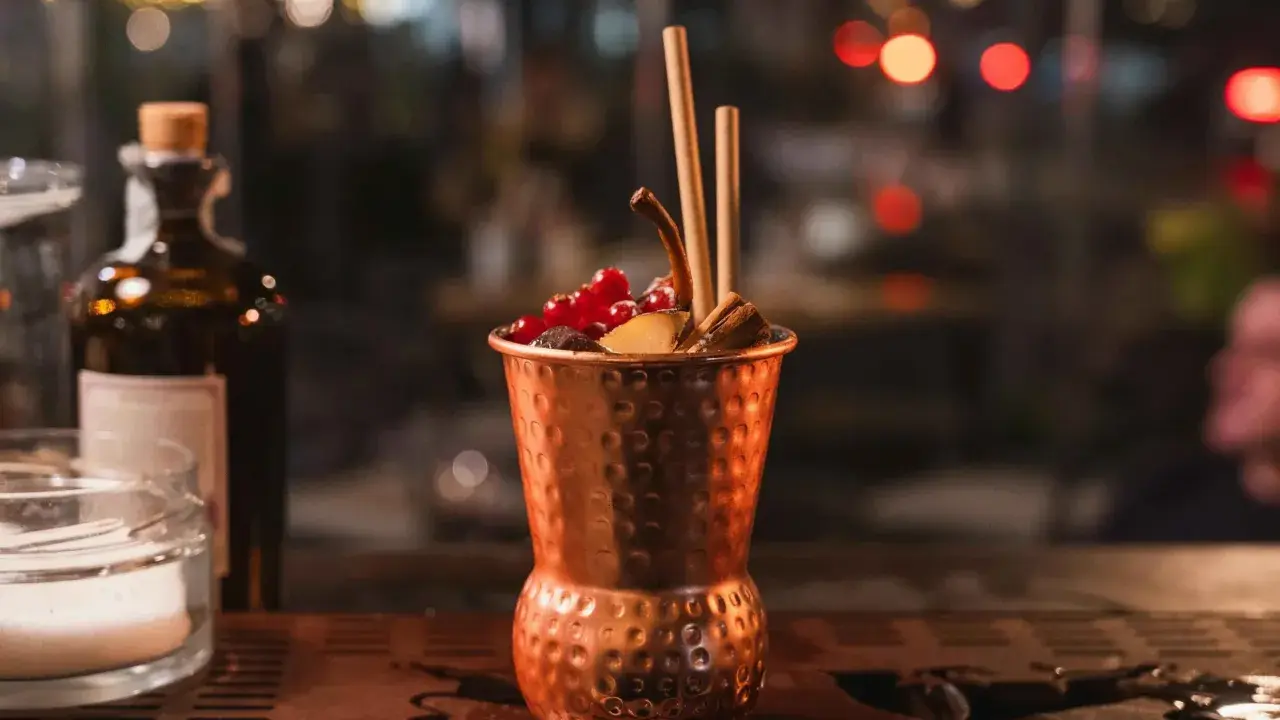 Cocktail in rame, decorato con frutti rossi e cannella, perfetto per un aperitivo Milano Marittima.