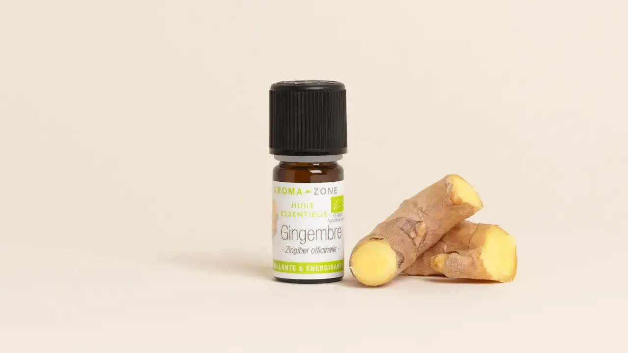 Flacon d'huile essentielle de gingembre bio, aux côtés de morceaux de rhizomes frais. Un concentré de vitalité.
