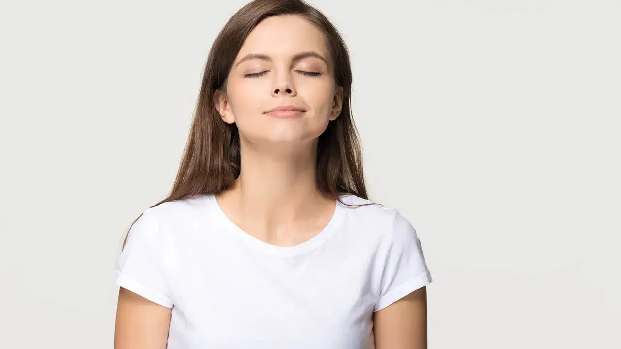 Frau mit geschlossenen Augen, die tief durchatmet. Eine Übung zur Lippenbremse kann bei Asthma helfen, die Atmung zu kontrollieren.