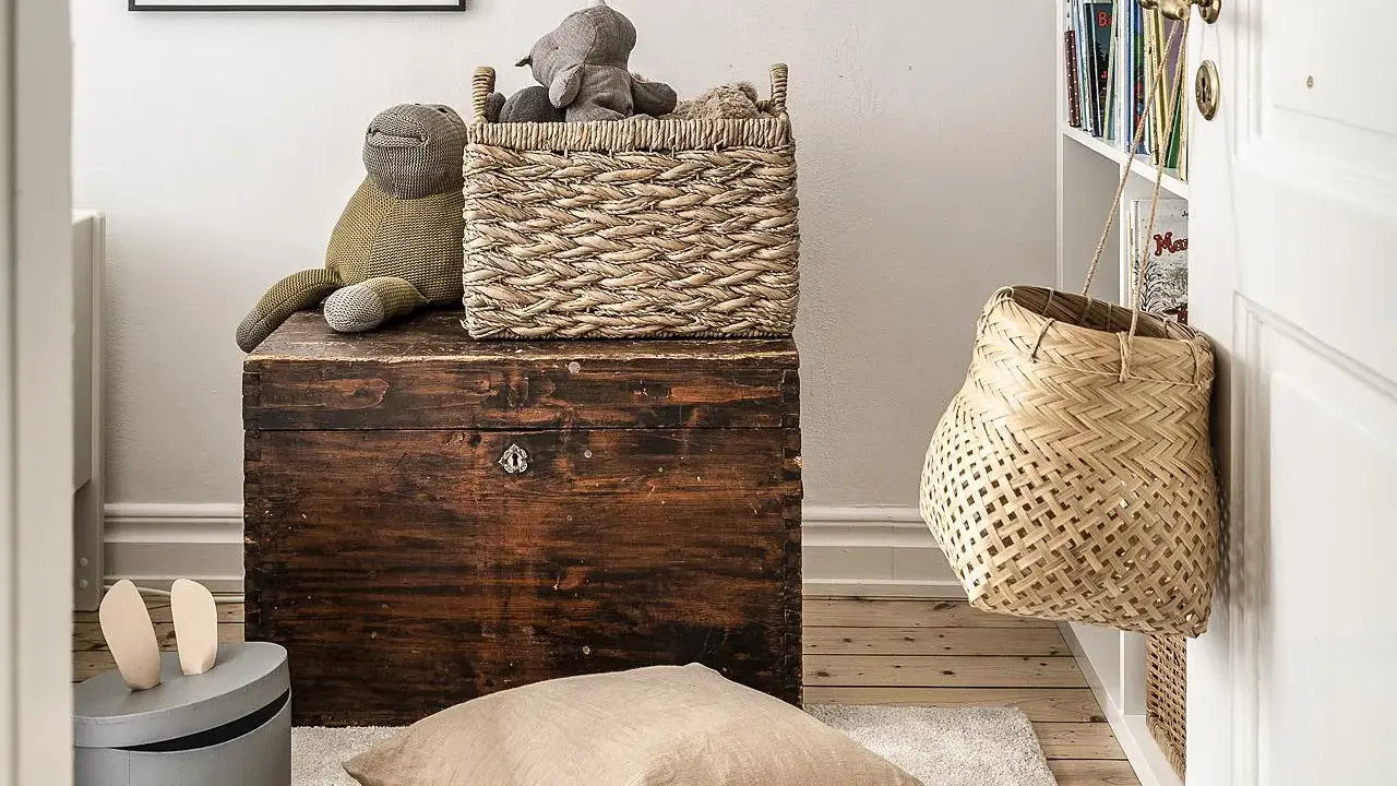 Cesti di vimini per idee arredare con stile: un cesto intrecciato sopra un baule antico, un altro appeso alla porta.