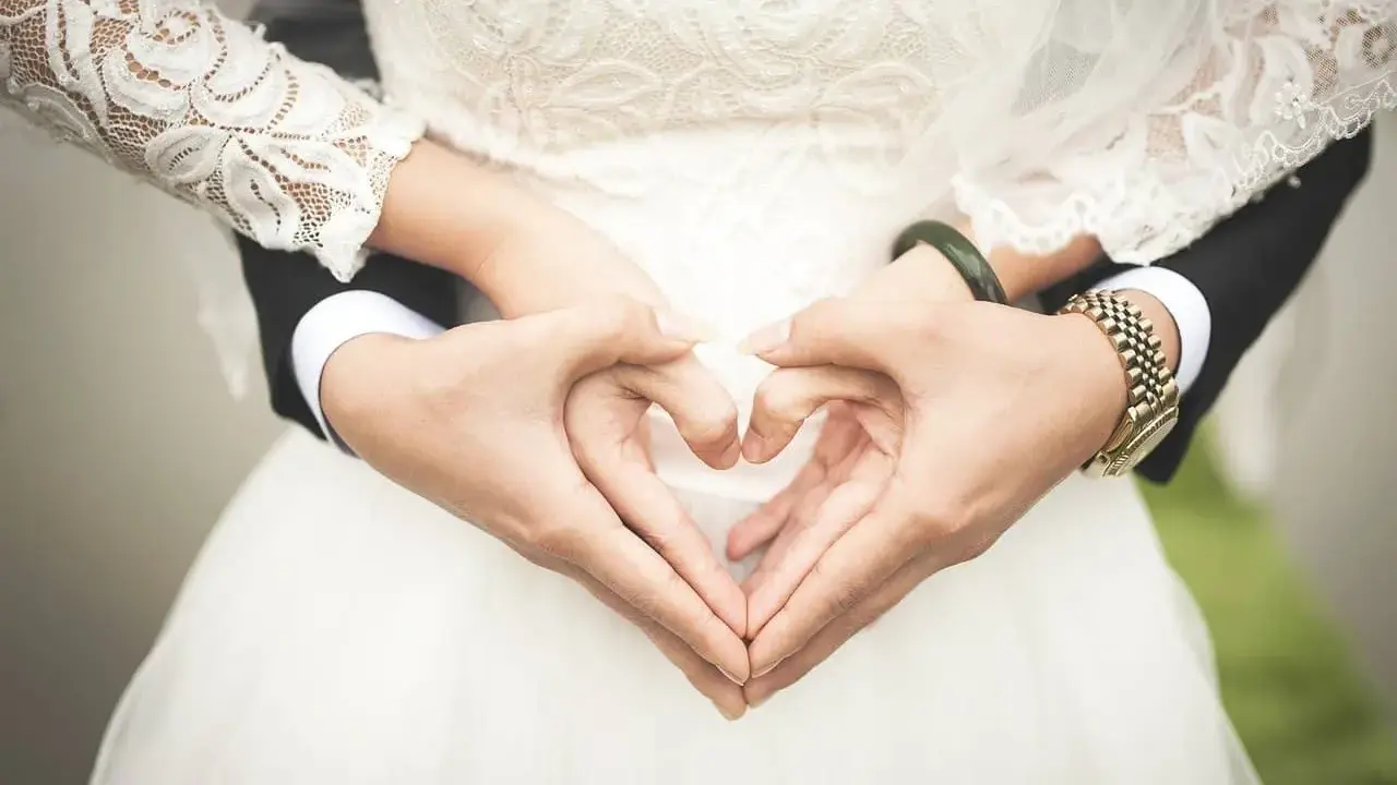 Manos formando un corazón sobre el vestido de novia, símbolo de una boda de platino.