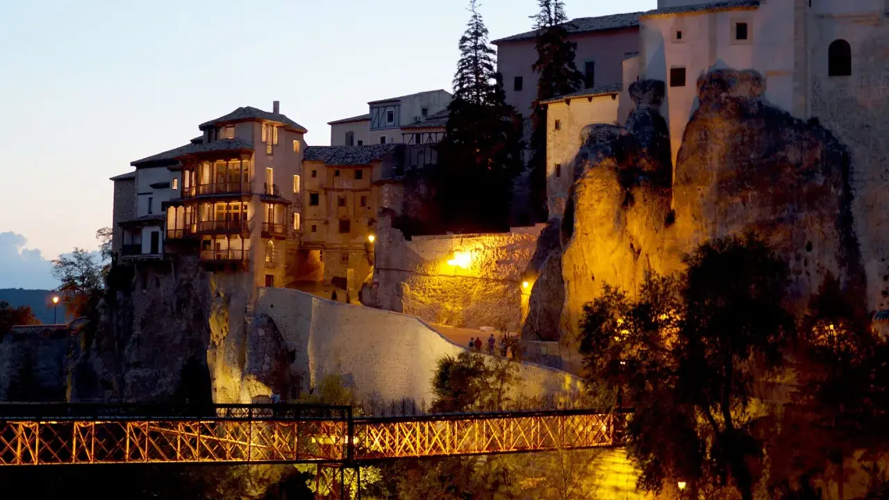 El puente de San Pablo en Cuenca, iluminado de noche, conecta las casas colgantes con la ciudad.