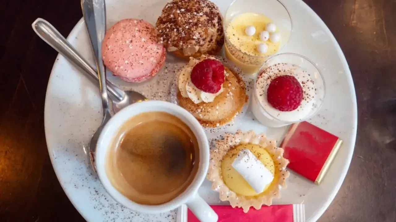 Assortiment de spécialités culinaires parisiennes : macarons, éclairs, tartellettes, verrines et café. Un délice pour les yeux et les papilles.