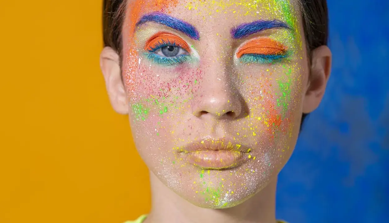 Rostro con maquillaje vibrante y purpurina. ¿Cómo quitar la purpurina de la cara? Este look es un desafío.