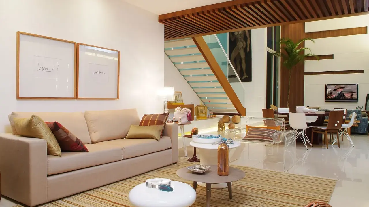 Elegantes salones marrones y beige con sofá, mesas auxiliares, alfombra a rayas y una escalera moderna.
