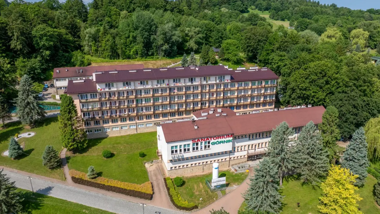 Sanatoria pełnopłatne w Iwoniczu-Zdroju: rozległy kompleks budynków otoczony zielenią, z widocznym napisem "Sanatorium Górnik".