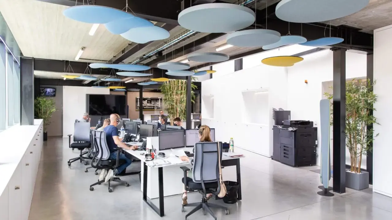 Bureau moderne avec des employés concentrés, des panneaux acoustiques colorés au plafond pour réduire le bruit au travail.