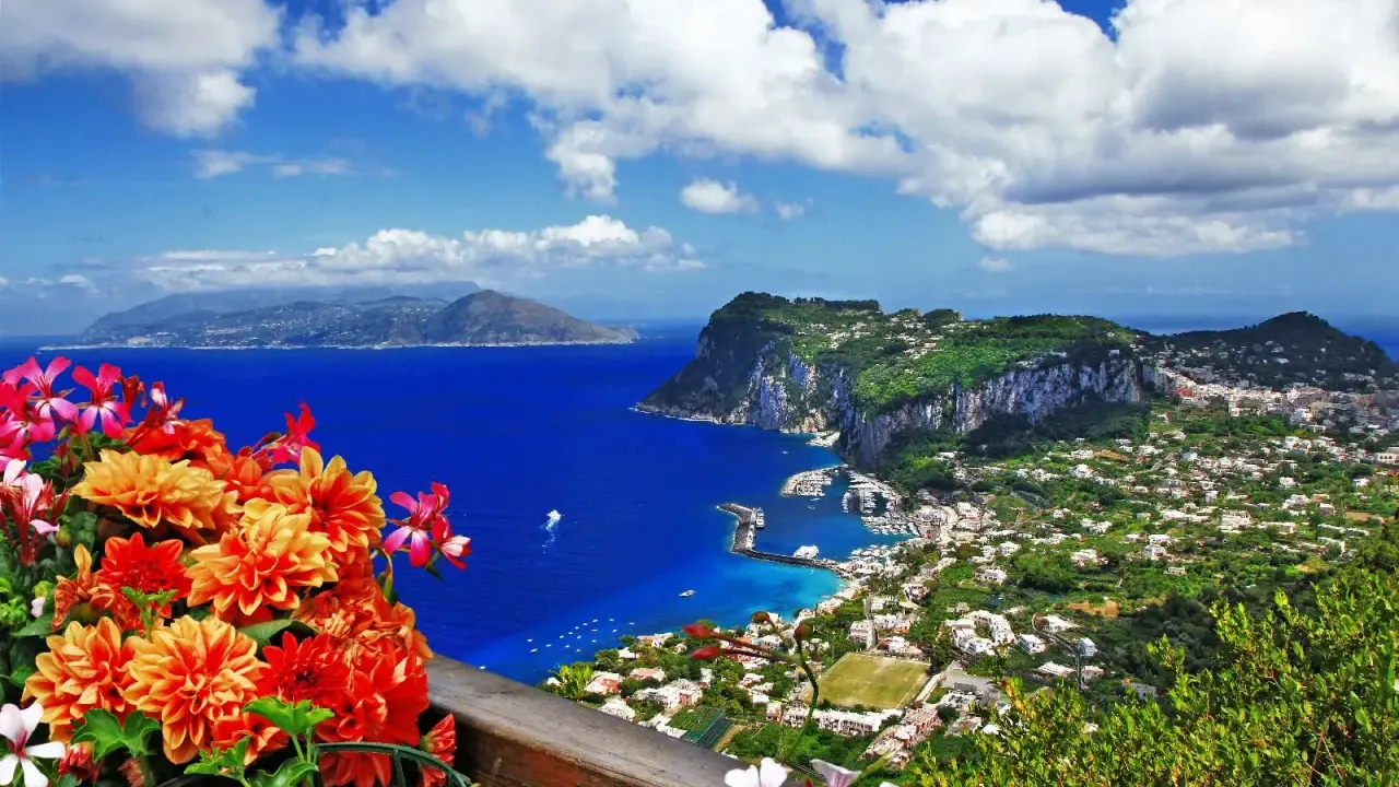 Splendida capri vista da napoli, con fiori colorati in primo piano e il mare blu intenso.