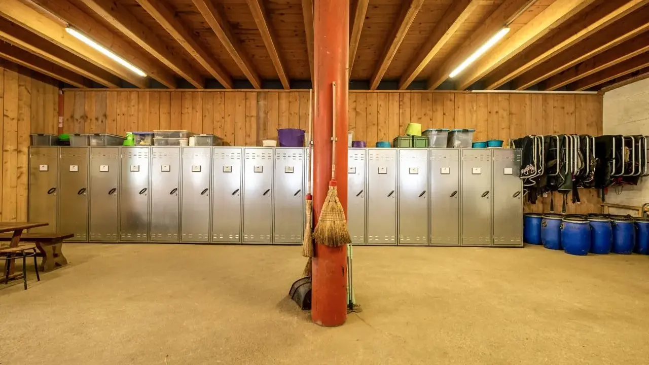 Reihe von Spinden, ideal zum Sattelschrank organisieren. Besen lehnen an rotem Pfosten.