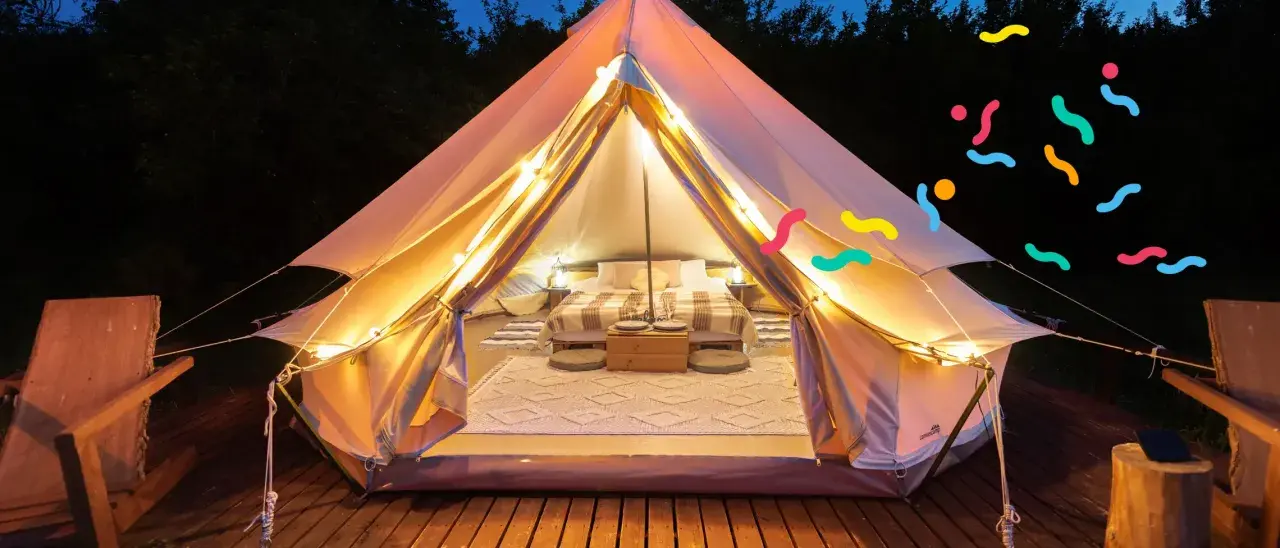 Tenda accogliente illuminata, perfetta per un'esperienza di glamping per famiglie. Letto comodo, tappeti e luci creano un'atmosfera magica.
