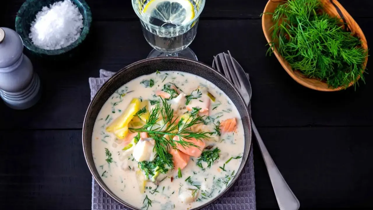 Krämig fisksoppa med lax och dill, en av många lyxiga fiskrecept. Serveras med citronvatten och havssalt.
