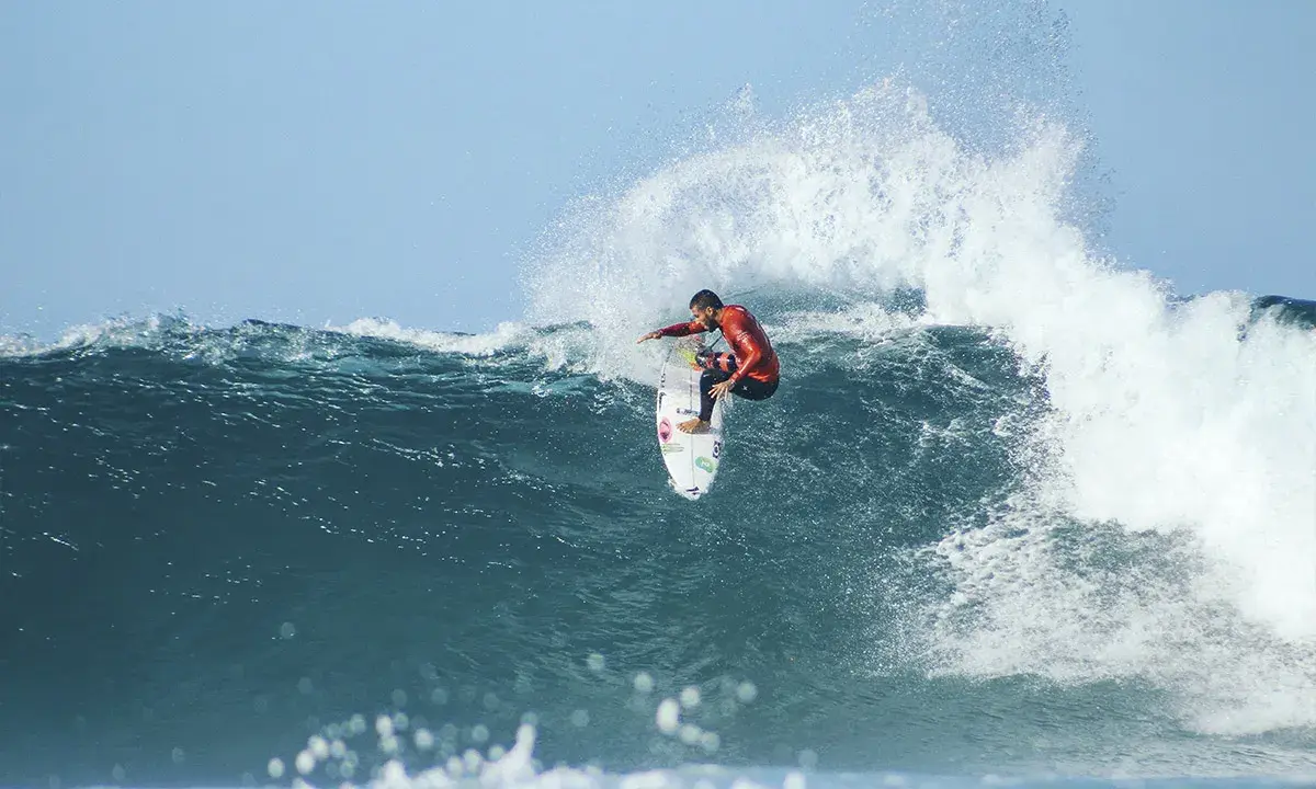 Surfer in rotem Neoprenanzug meistert eine riesige Welle beim Mauritius Surf.