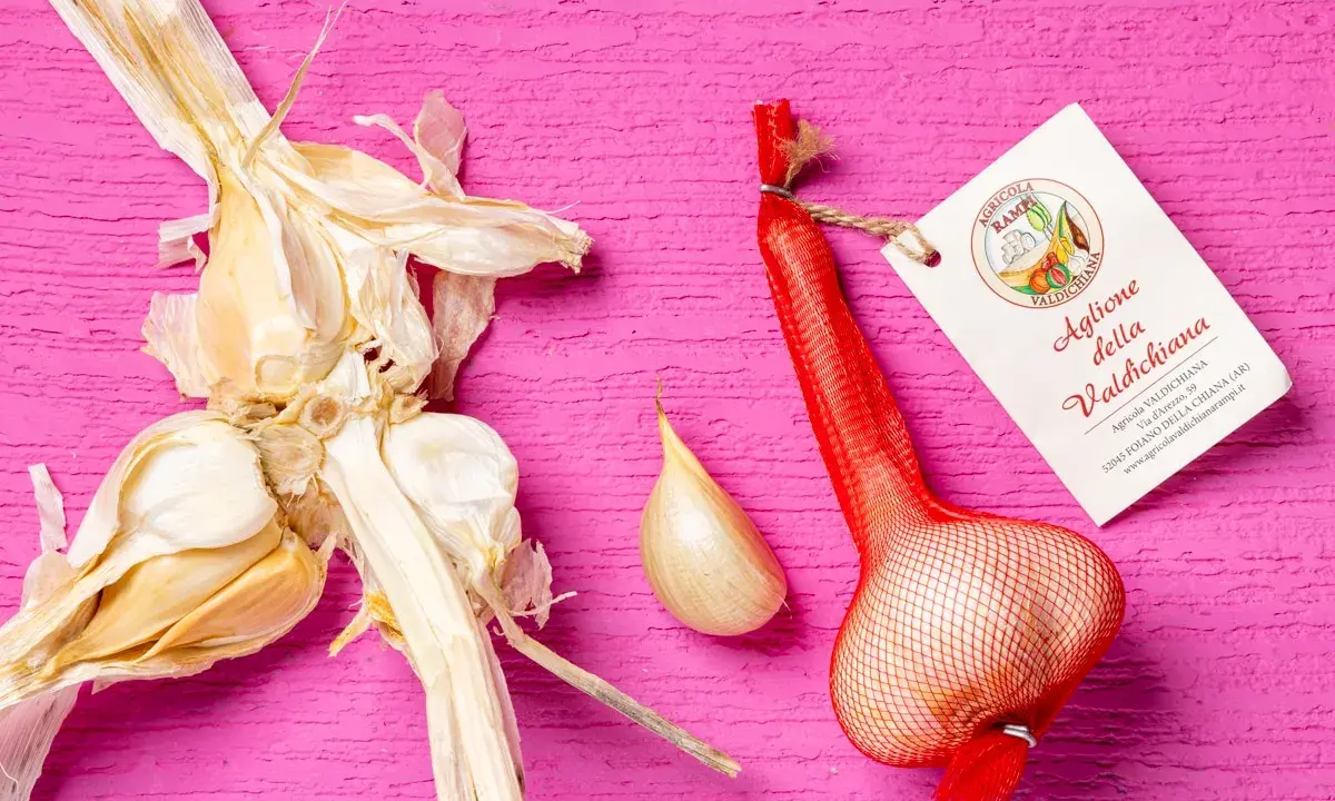 Aglione della Valdichiana, perfetto per le tue aglione ricette. Un bulbo intero e uno spicchio su sfondo rosa.