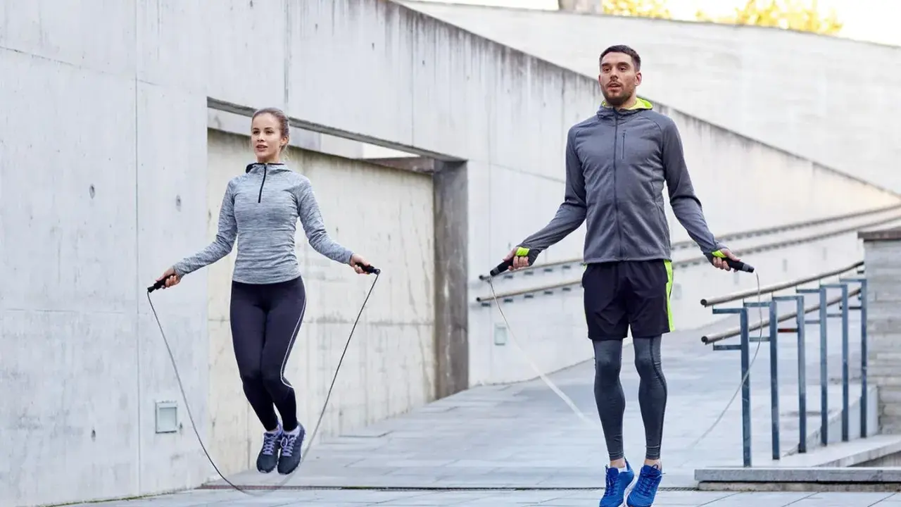 Ein Paar macht ein intensives **Springseil Workout** im Freien vor einer Betonwand.
