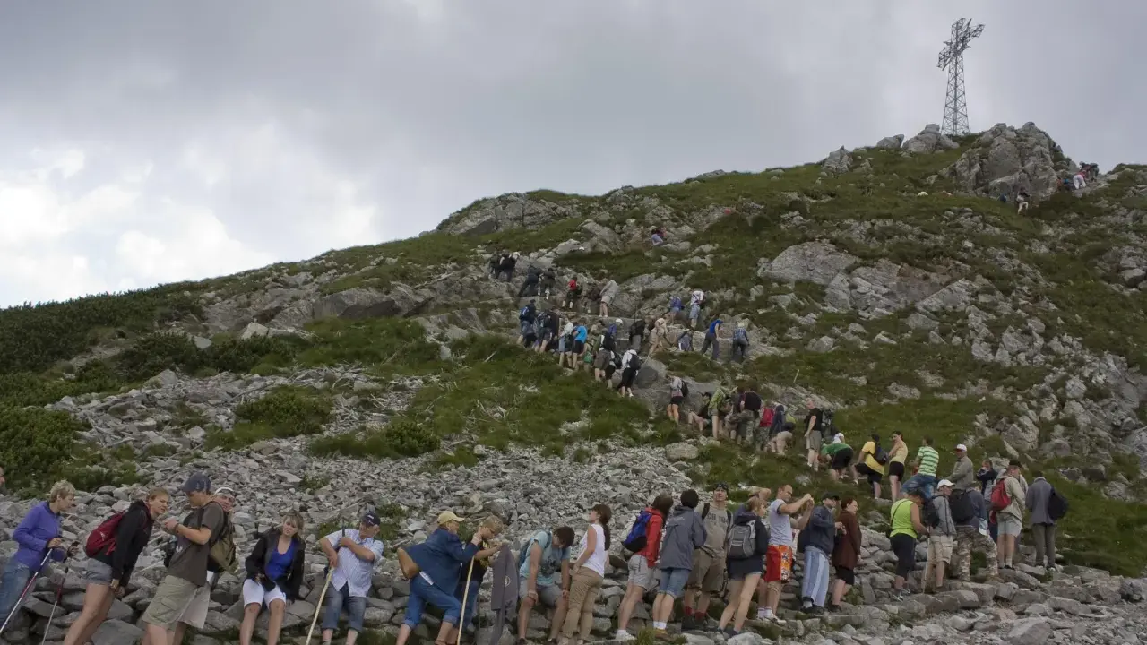 Tłum turystów wspina się na Giewont. Kolejka do wjazdu na szczyt jest długa, a cennik pewnie nie jest tani.