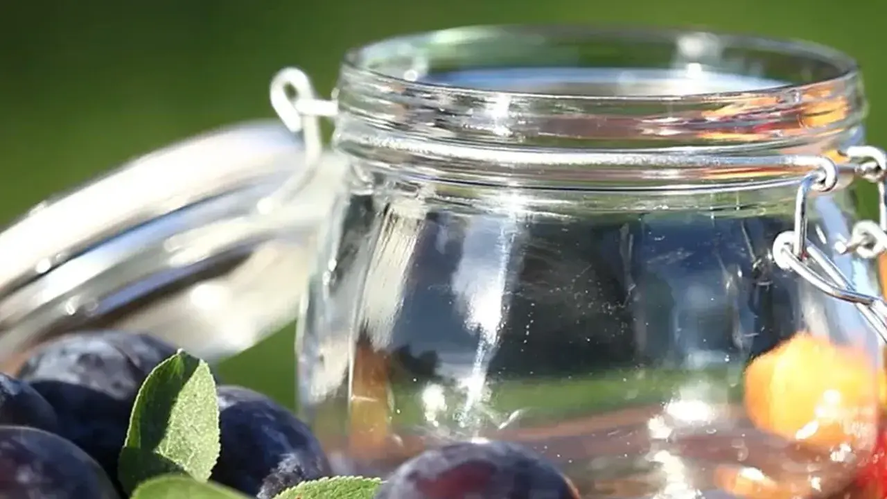 Ein Glas mit frischen Pflaumen und Beeren, bereit für Marmelade. Vorsicht bei der Zubereitung, um Botulismus zu vermeiden.