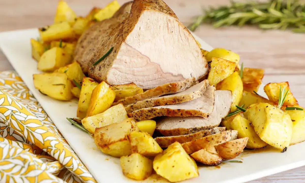 Arrosto di vitello al forno, succulento e dorato, servito con patate arrosto croccanti e profumate al rosmarino.