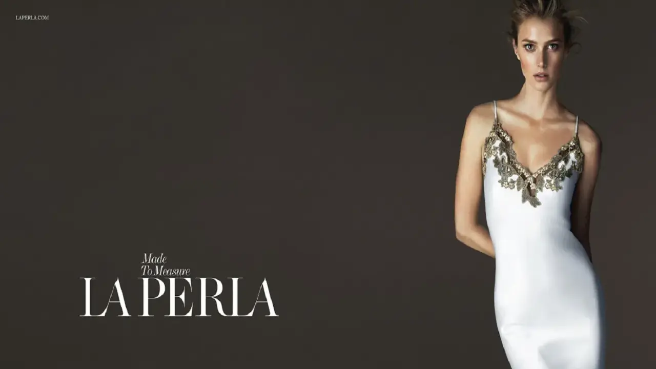 Model in a white slip dress with gold lace trim, with "LA PERLA" logo.