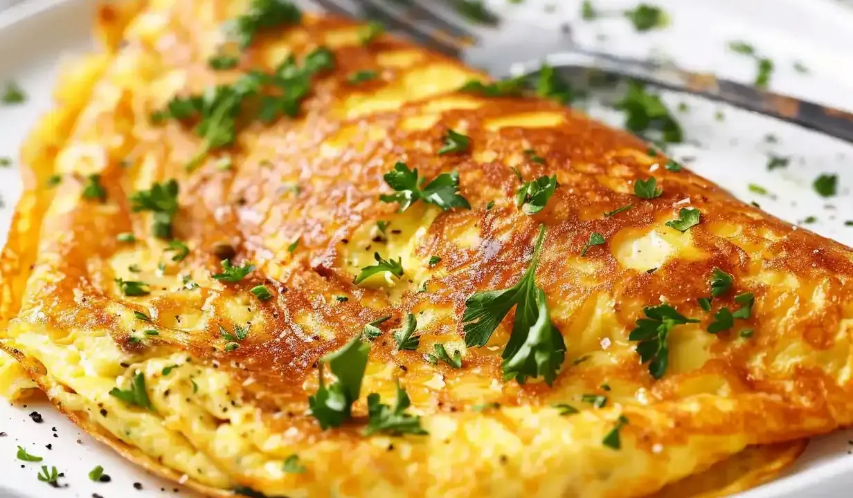 En gyllene omelett, perfekt för ett snabbt omelett recept, toppad med färsk persilja och en nypa salt.