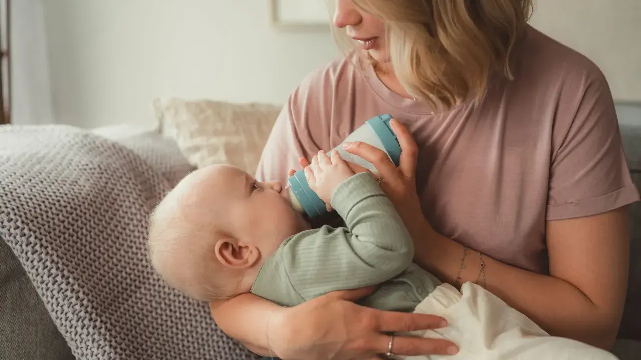 Mutter füttert Baby mit Flasche. Das Baby trinkt langsam, um die Verdauung zu unterstützen.