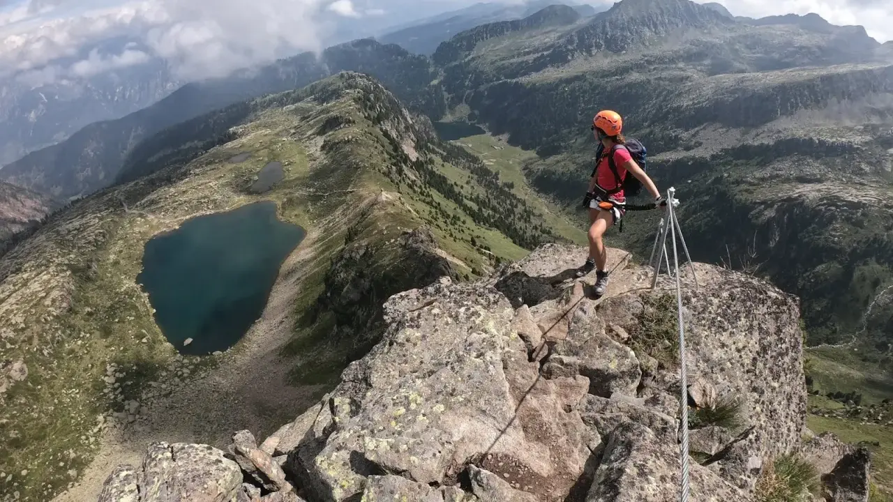 Escursionista in cima a una cresta rocciosa con vista sui laghi di Bombasel e sulle montagne circostanti.