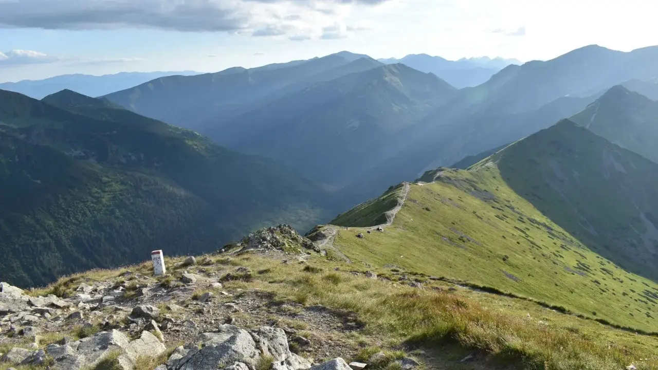 Widok na pasmo górskie Tatr z zielonymi zboczami i kamienistym szlakiem.