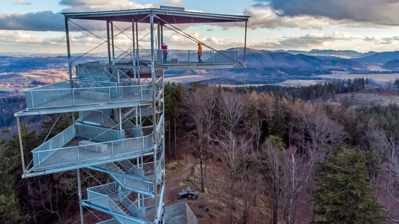 Trójgarb wieża widokowa oferuje zapierający dech w piersiach widok na okoliczne wzgórza i lasy. Dwie osoby podziwiają panoramę z najwyższego tarasu.