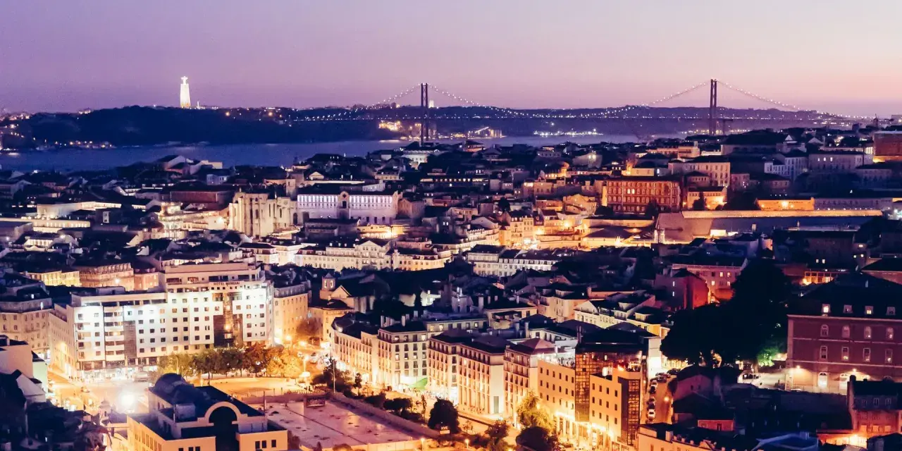 Lichter der schönsten Stadt Portugals, Lissabon, funkeln bei Dämmerung. Cristo Rei Statue und Ponte 25 de Abril Brücke im Hintergrund.