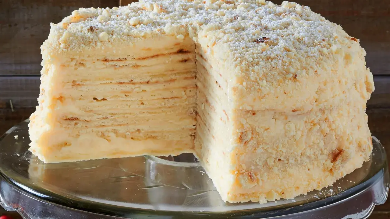 Ein aufgeschnittener Napoleon Kuchen mit vielen dünnen Schichten und cremiger Füllung, bestreut mit Krümeln.