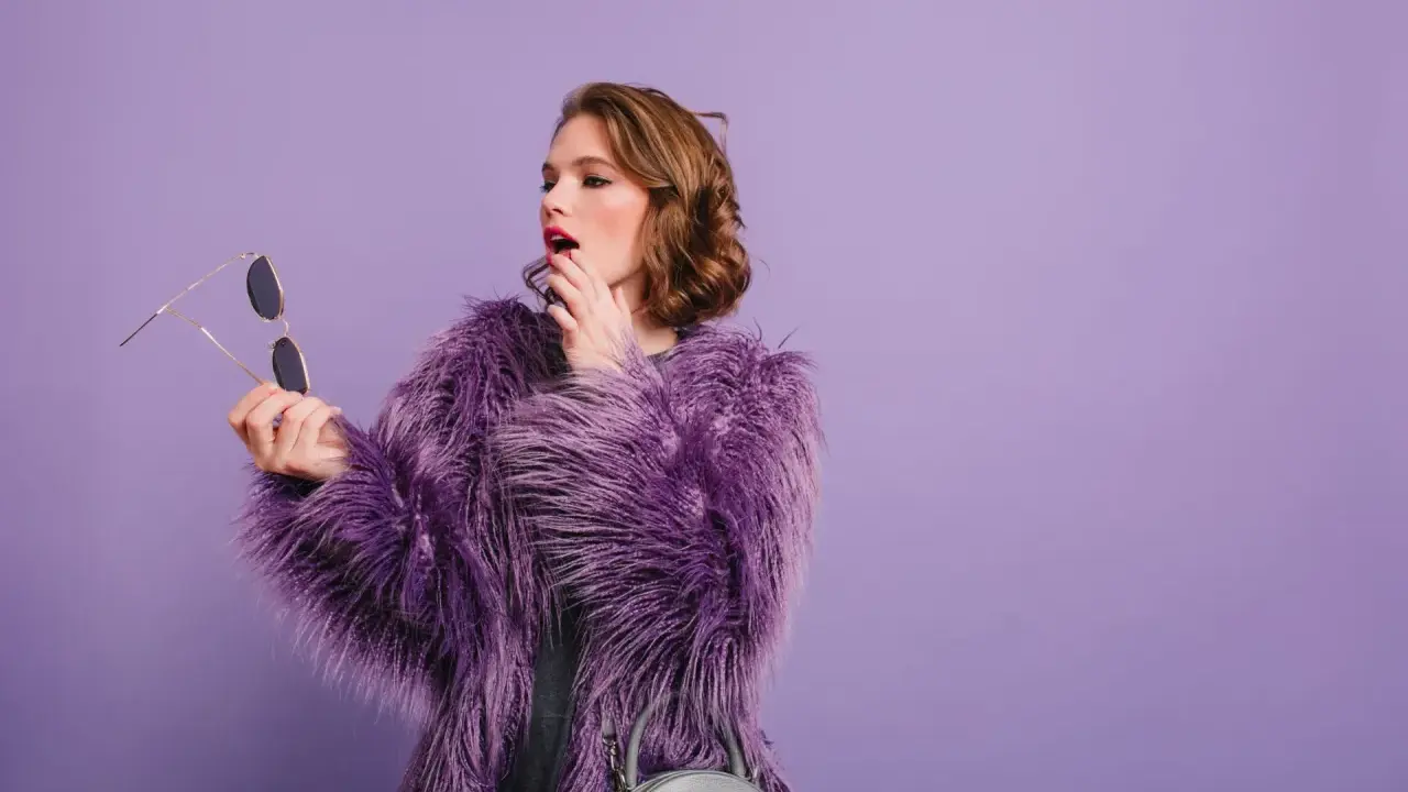 Chica con abrigo morado y maquillaje vibrante, lista para un evento.