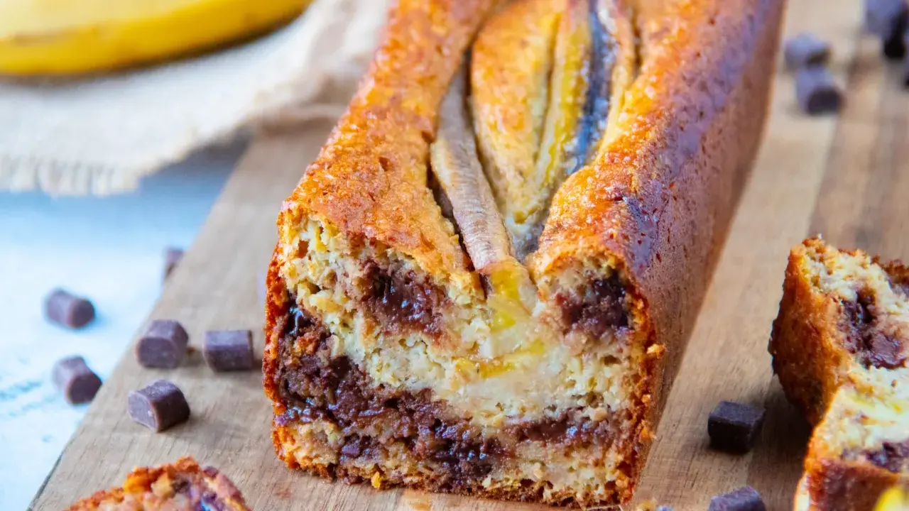 Un délicieux banana bread healthy, garni de pépites de chocolat, avec des bananes entières sur le dessus.