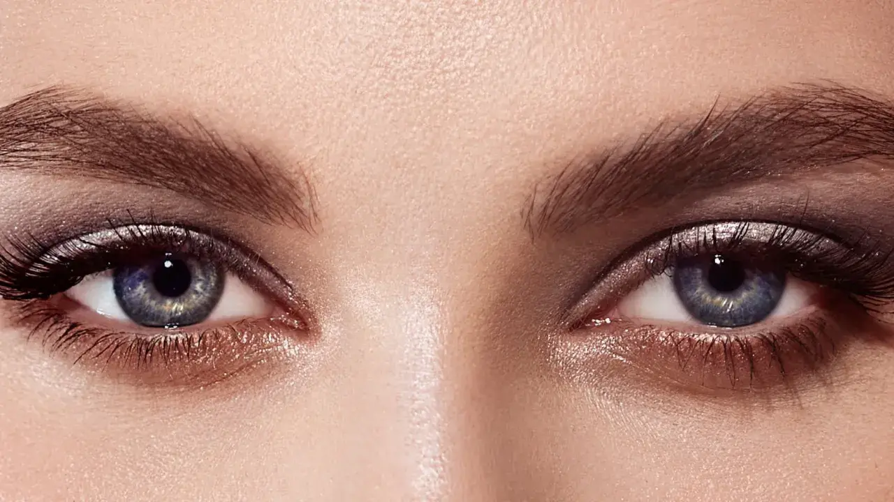 Ojos con un cautivador maquillaje con sombras azules y plateadas, realzados por pestañas largas y definidas.