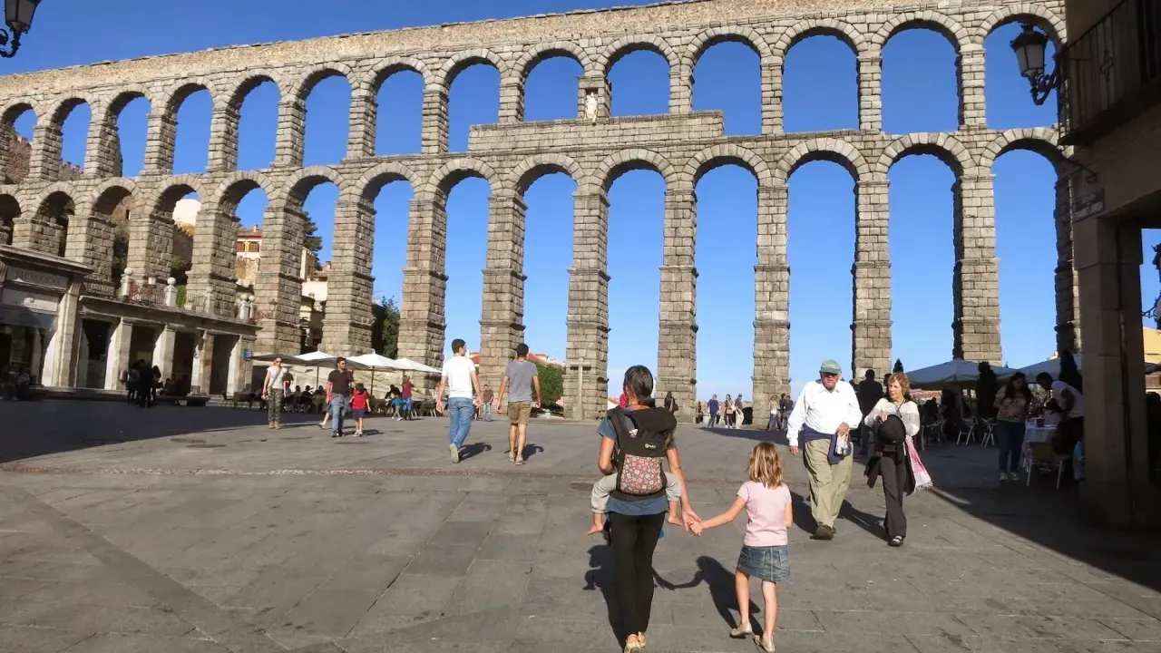 Familia pasea bajo el Acueducto de Segovia, un lugar ideal que ver en Segovia con niños.