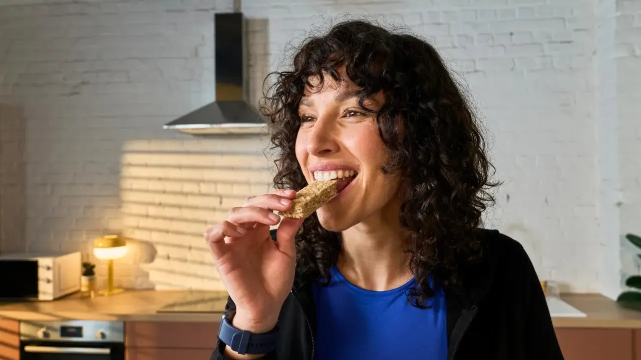 Frau isst einen Riegel, die perfekte Energie für das, was essen vor dem Training.