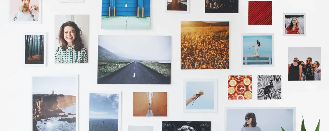 Un collage di fotografie su una parete bianca: paesaggi, ritratti, natura. Un'idea su come esporre fotografie in modo creativo.