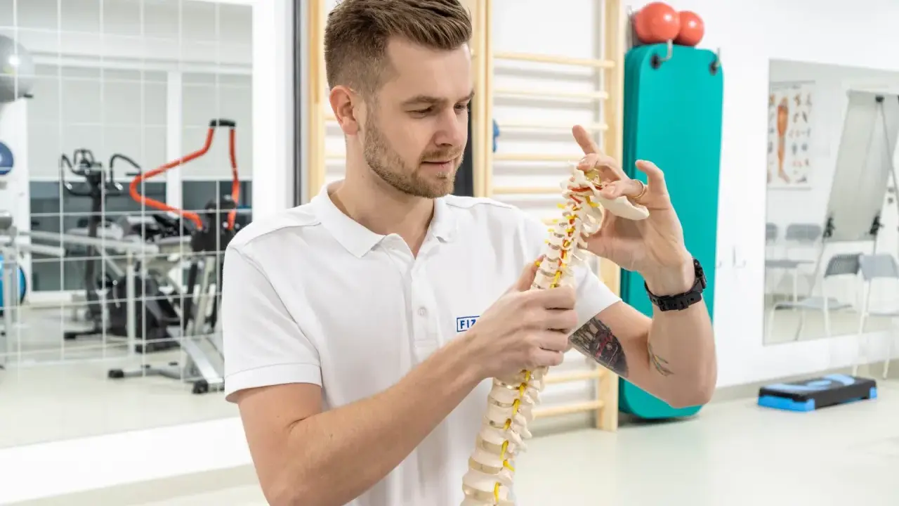 Fizjoterapeuta z wyższej szkoły rehabilitacji w Warszawie pokazuje model kręgosłupa.