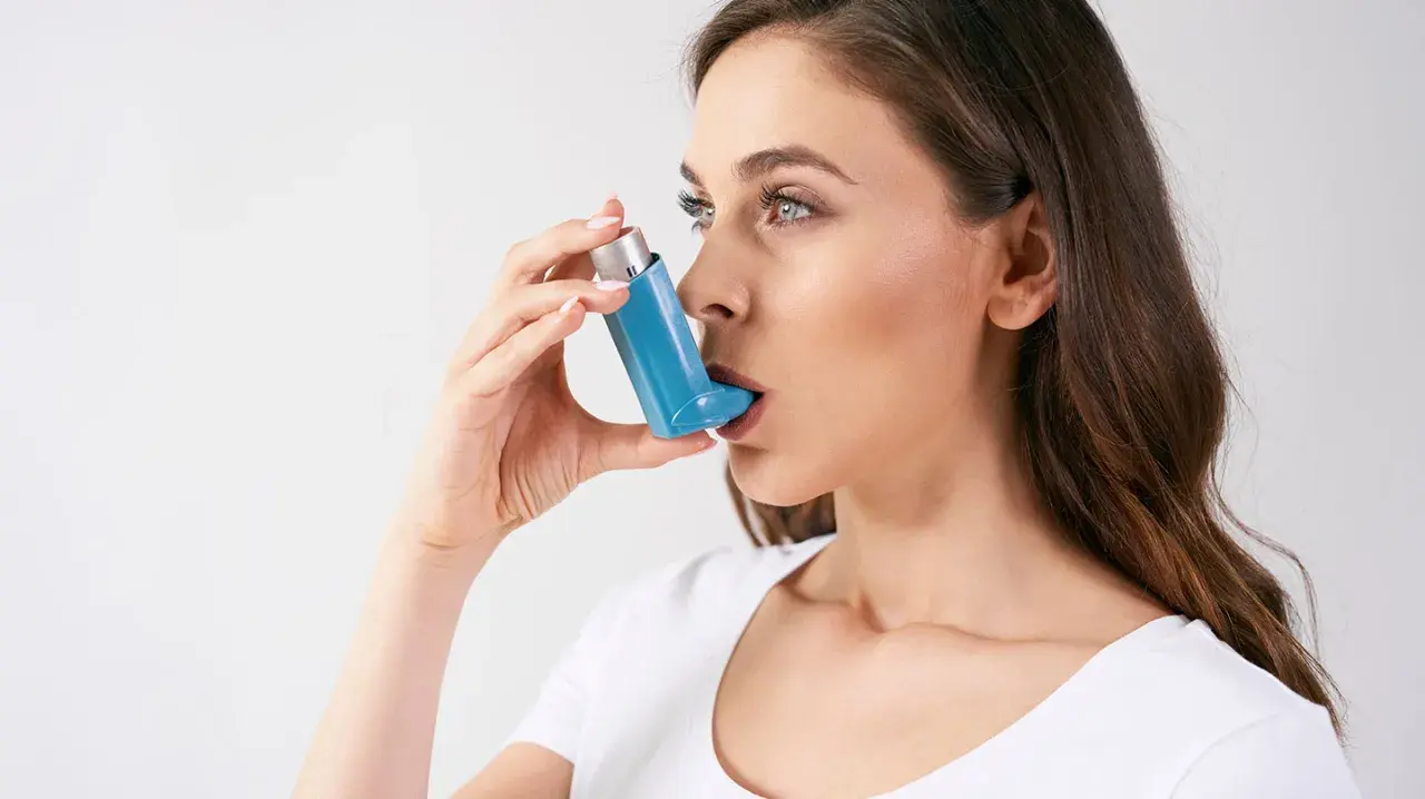 Frau mit Asthmaspray, das sie falsch anwendet. Die Anwendung ist nicht korrekt, was die Wirksamkeit beeinträchtigt.