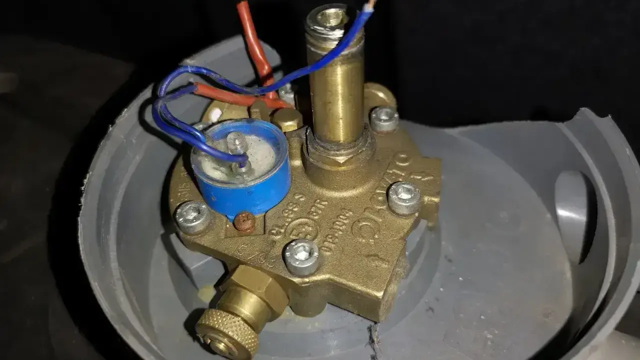 Uszkodzony elektrozawór LPG. Widoczne luźne przewody i korozja, potencjalne objawy awarii.