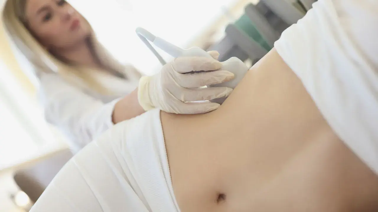 Ärztin untersucht Bauch einer Frau mit Ultraschall, um Schmerzen linke Seite Taille zu diagnostizieren.