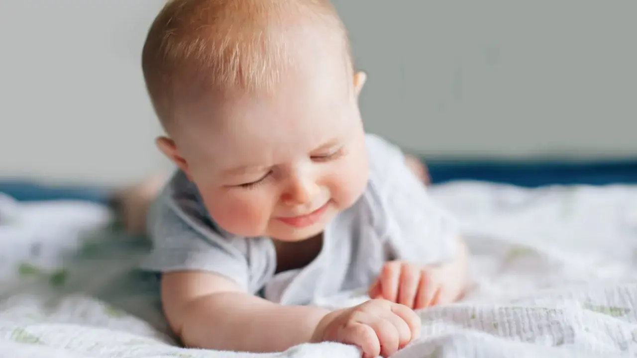 Ein süßes Baby liegt auf dem Bauch, die Augen geschlossen, als würde es die Welt entdecken. Ein Zeichen des baby 6 wochen wachstumsschub.